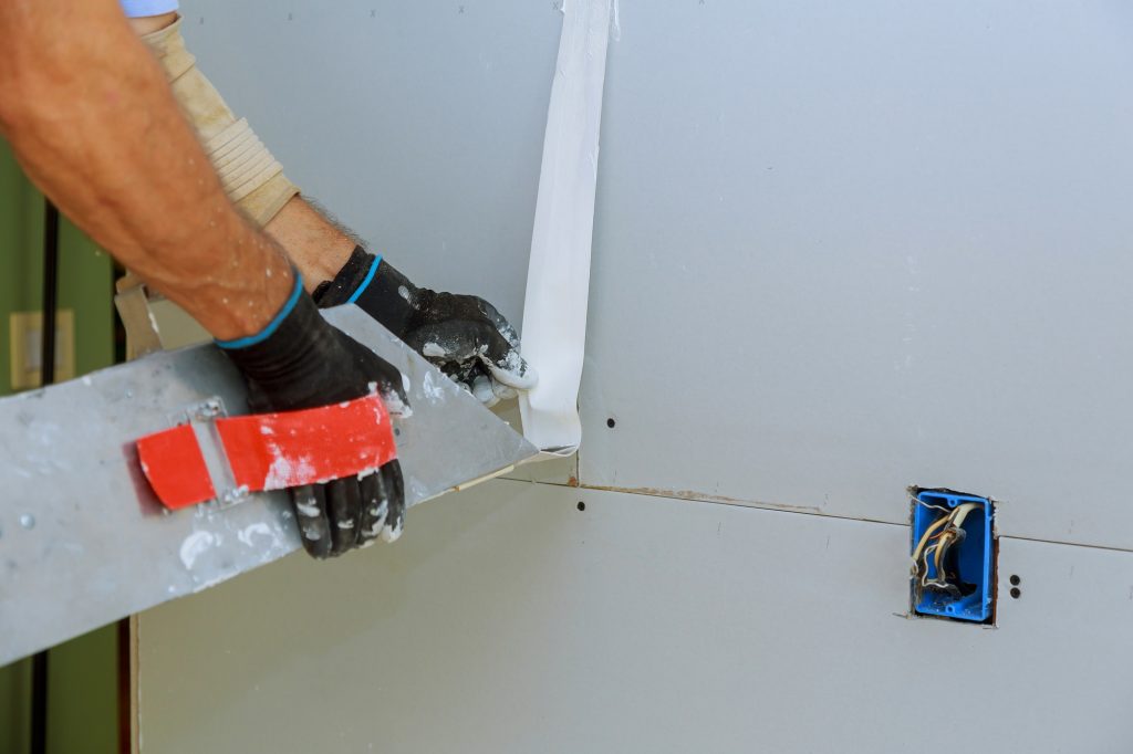 Worker plastering gypsum board wall apartment interior construction
